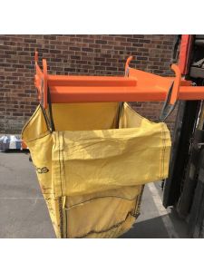 Forklift bulk bag lifter attachment holding a yellow heavy-duty sack for safe material handling in warehouses and construction sites.