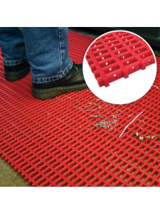 Anti-slip modular floor matting in red with drainage holes, shown underfoot in an industrial environment.