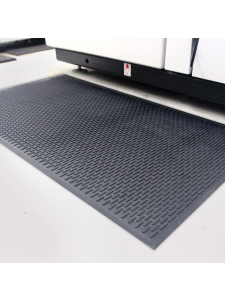 Black anti-fatigue rubber mat positioned in front of industrial machinery for operator comfort.