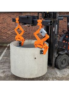 Forklift lifting concrete pipe using orange mechanical pipe grab attachment.