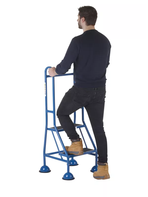 Man standing on three-step safety stool with extended handrail