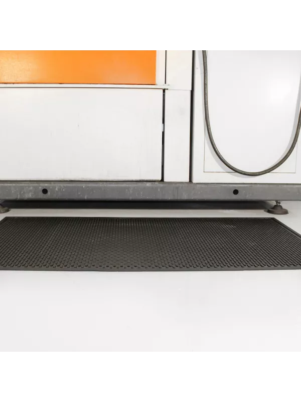 Heavy-duty rubber floor mat placed beneath industrial equipment for slip resistance and comfort.