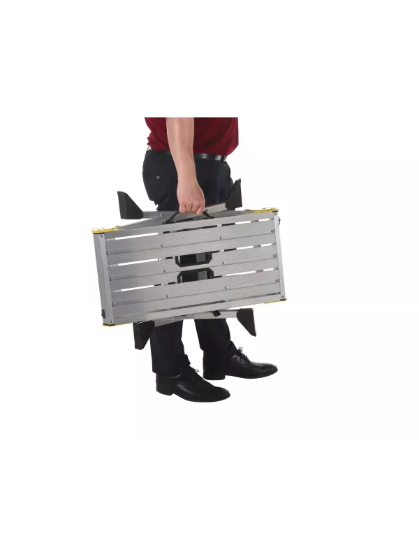 Person carrying folded aluminium work platform by integrated handle.