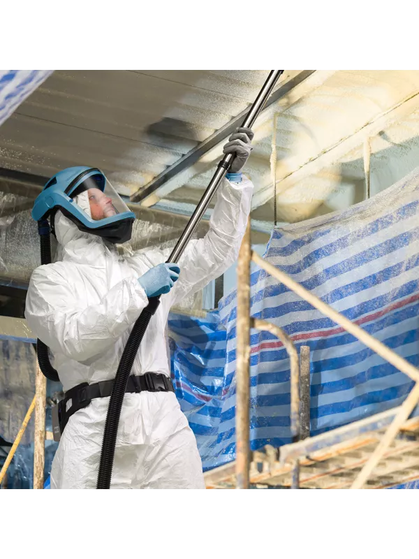 Operator in protective suit using a Numatic vacuum for insulation or dust removal.