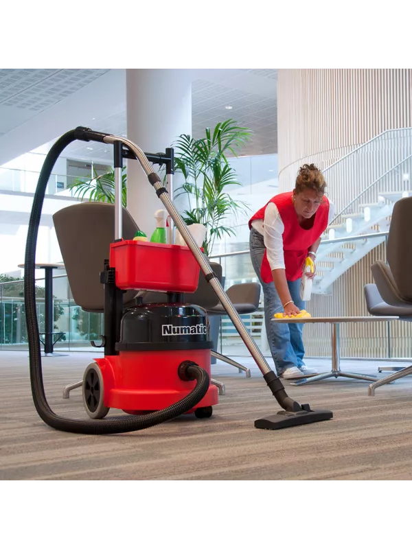 Cleaner using a red Numatic vacuum with caddy during commercial cleaning.