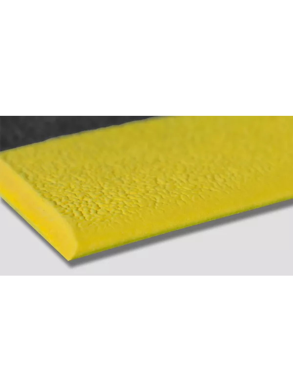 Close-up of yellow safety edge on anti-fatigue mat – durable cushioned matting for industrial use.