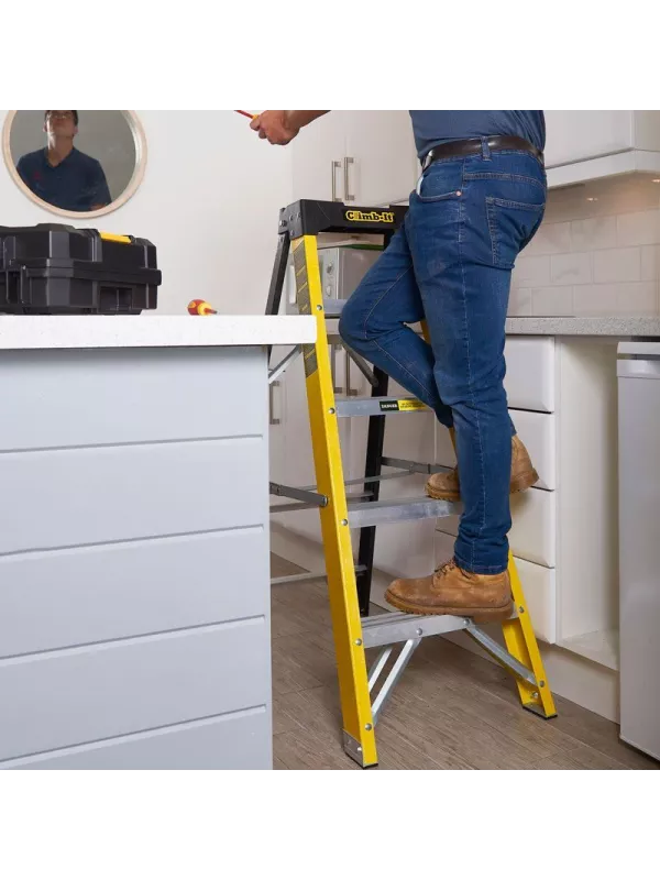 Person standing on yellow step ladder while working in a kitchen.