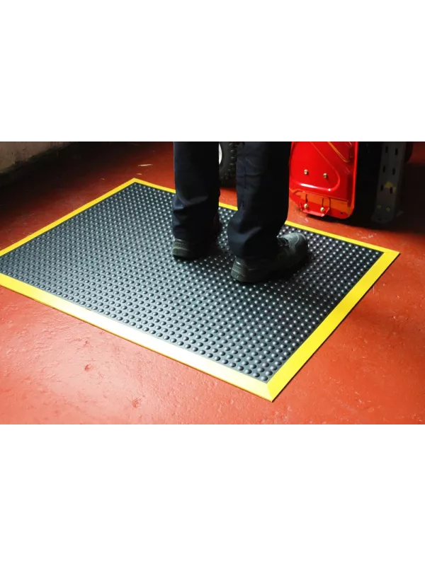 Anti-fatigue mat with textured surface and yellow safety border – slip-resistant industrial floor mat.