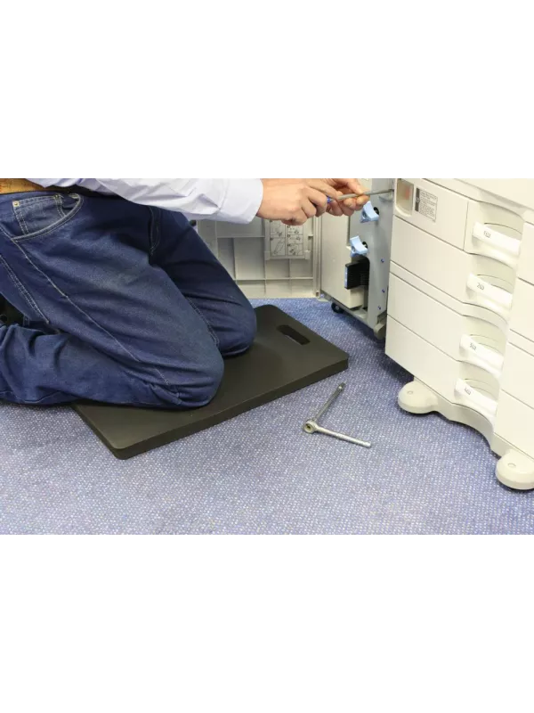 Worker using cushioned kneeling mat while servicing equipment – protective anti-fatigue mat for workplaces.