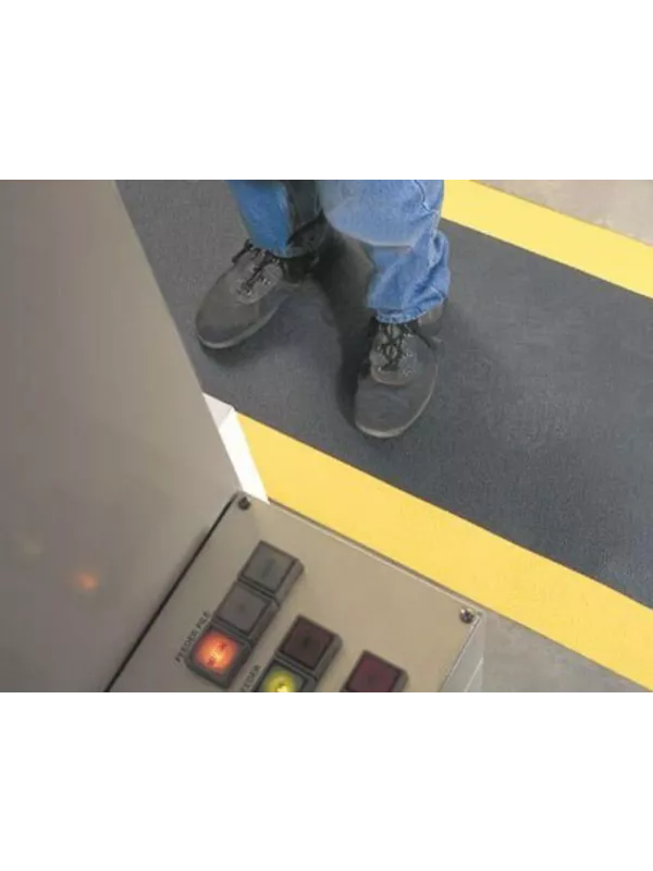 Worker standing on anti-fatigue safety mat with yellow edge – slip-resistant cushioned floor mat for factories and workshops.