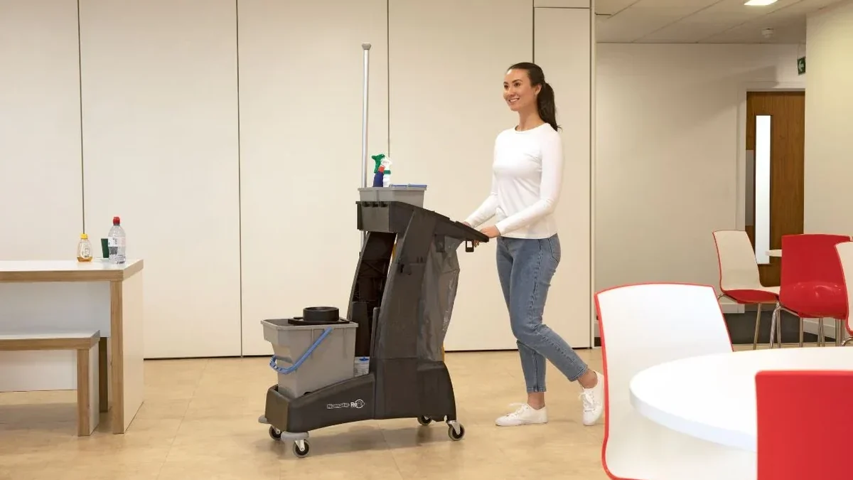 Cleaning operative using a janitorial trolley in a commercial workplace