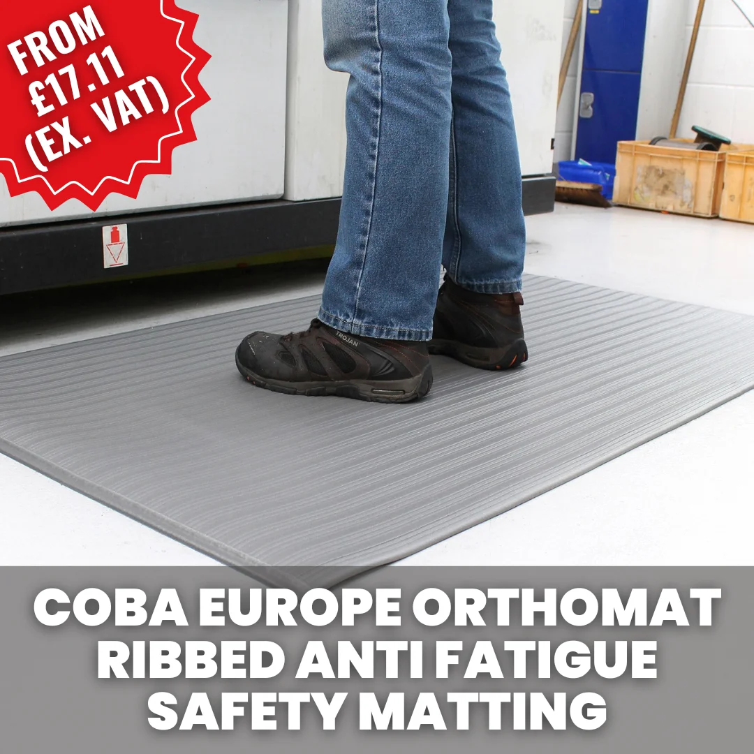 Worker standing on a COBA Orthomat ribbed anti-fatigue safety mat at an industrial workstation, providing cushioning and support for prolonged standing.