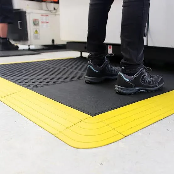 Solid Anti-Fatigue Workstation Matting Worker standing on solid anti-fatigue matting with yellow safety edging